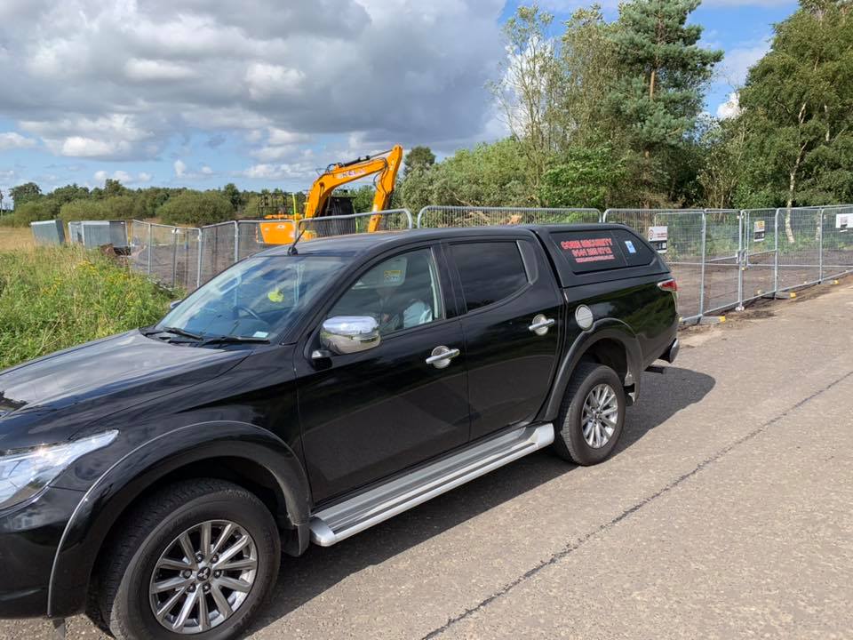 Core Security and Training branded patrol vehicle at a fenced construction site